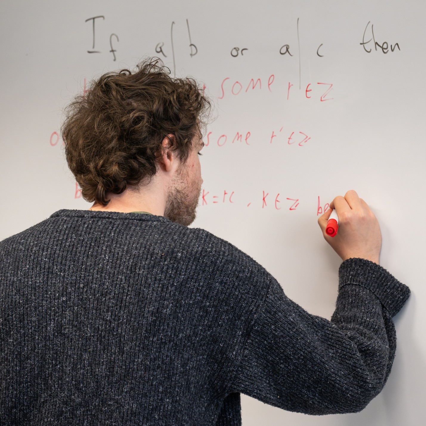 Maths student writing on a whiteboard.