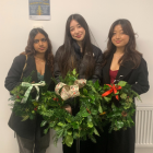 Image of three students holding festive wreaths