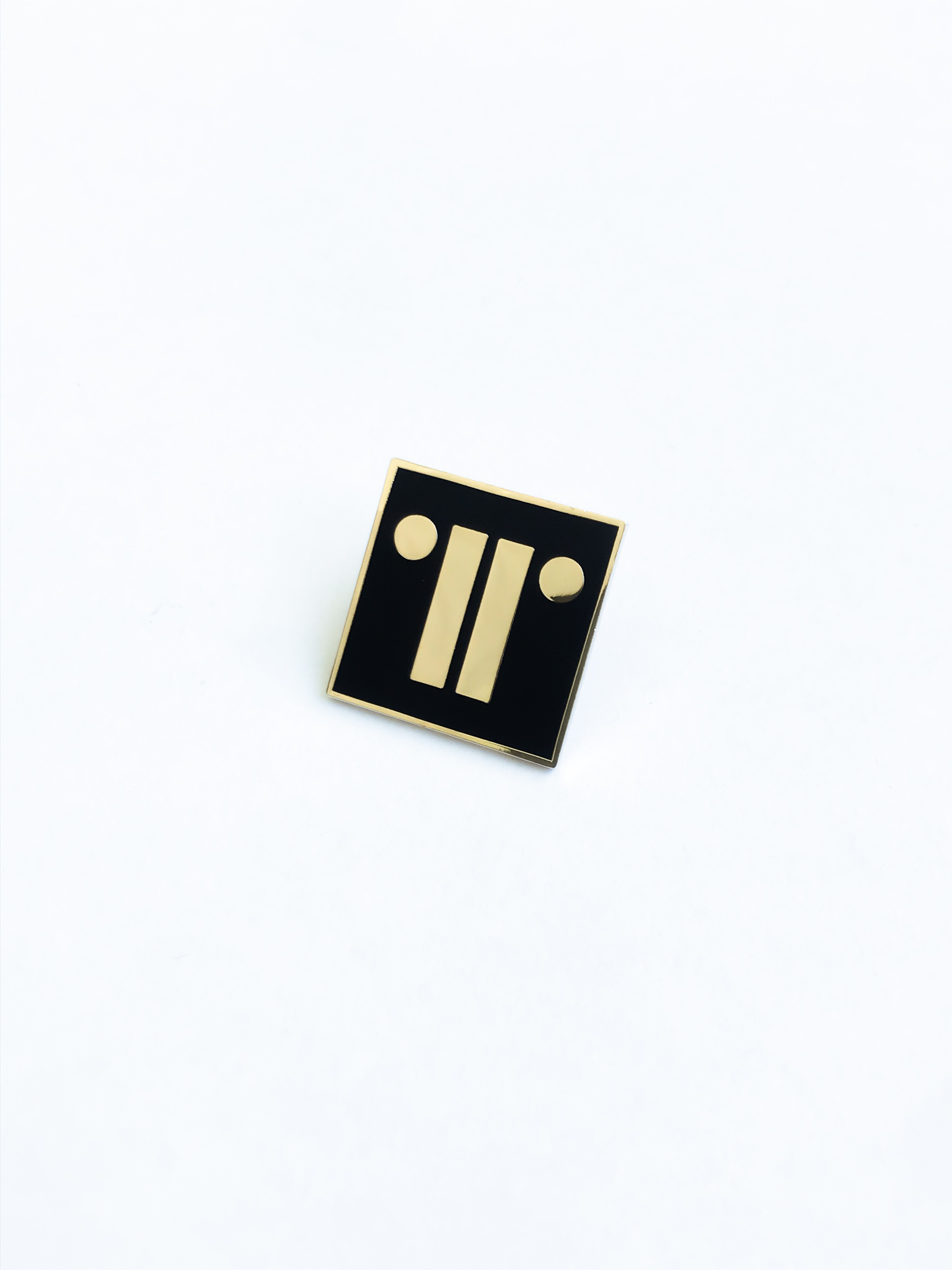 Gold badge with black enamel paint on white background.