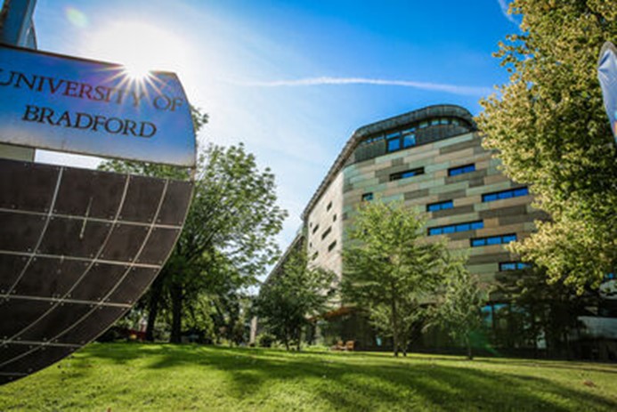 University of Bradford globe logo with School of Health building in background under blue skies