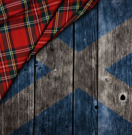 Red tartan fabric covering a Saltire flag painted on wooden planks