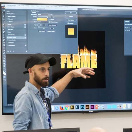 Teacher demonstrating graphic design using computer