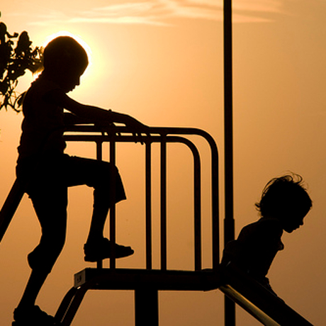 2 children playing on a slide in the evening sun