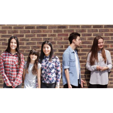 Smiling children standing in a line against a brick wall