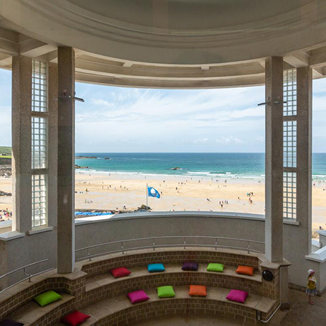 A view through a window at Tate St Ives to a beach and sea beyond.