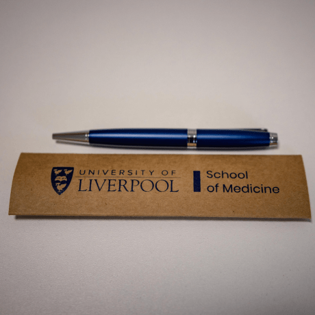Blue branded pen and kraft colour card sleeve laying on a white table