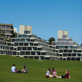 People on the grass in front of the Ziggurat Building on the UEA Campus