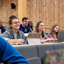 PGR Students in a lecture hall smiling and listening to the lecturer