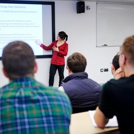 A person giving a lecture in a lecture theatre with people listening