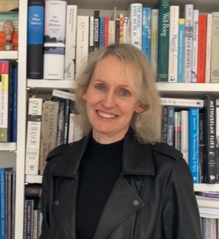 Helen Small standing in front of a colourful bookcase.