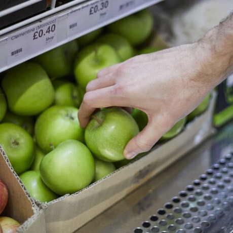 Hand reching to pick up an apple