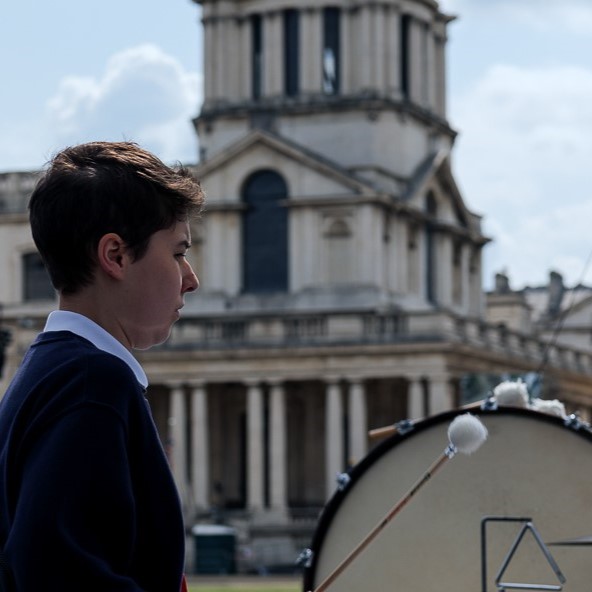 Young musicians on a stage, playing in front of the Old Royal Naval College.