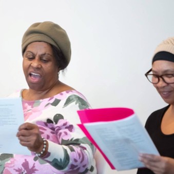 Two ladies singing from a booklet