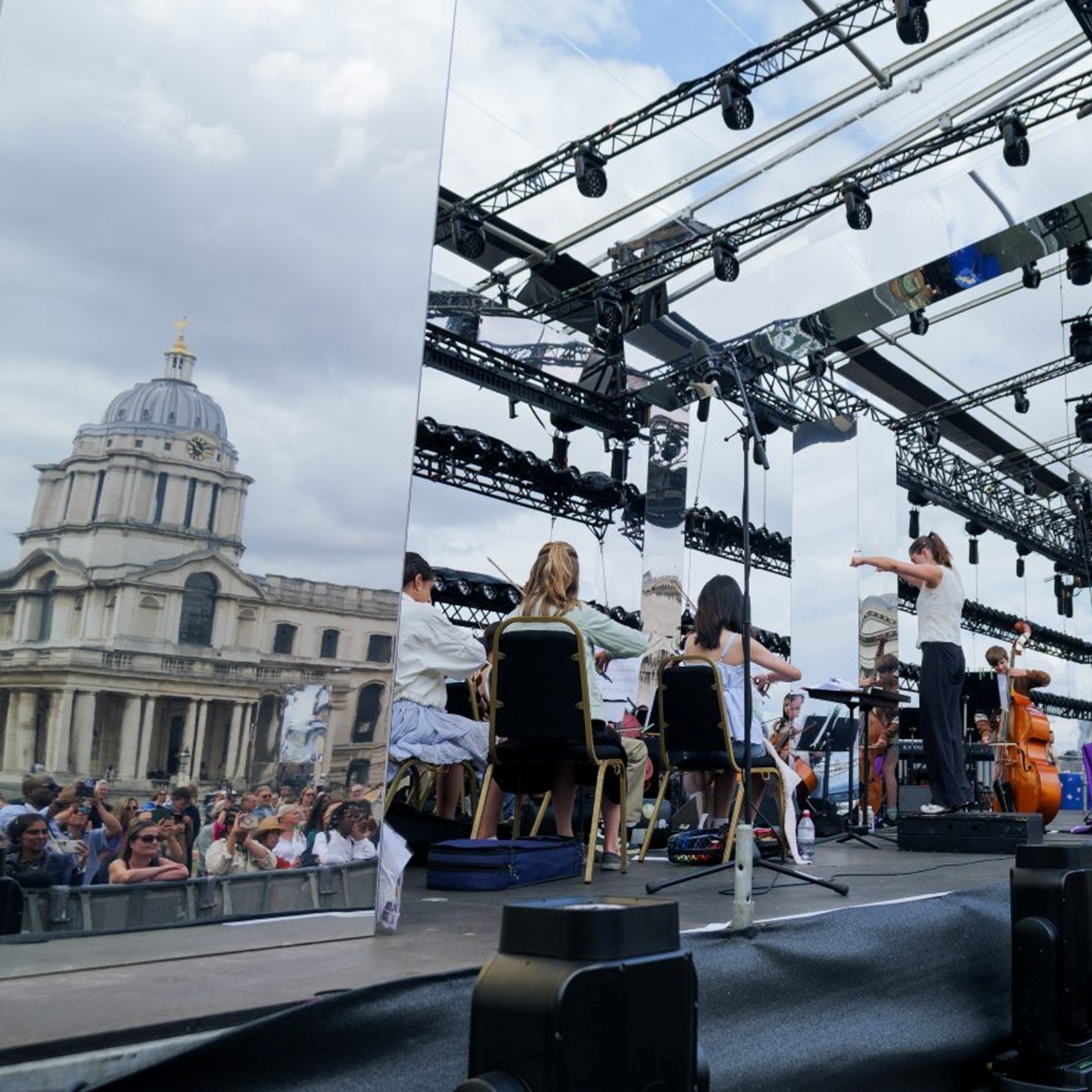 Young musicians on a stage, playing in front of the Old Royal Naval College.