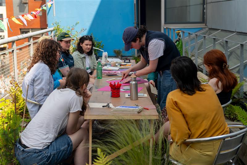 A group of people sitting at a table on a balcony. Image credit to Louis Haugh.