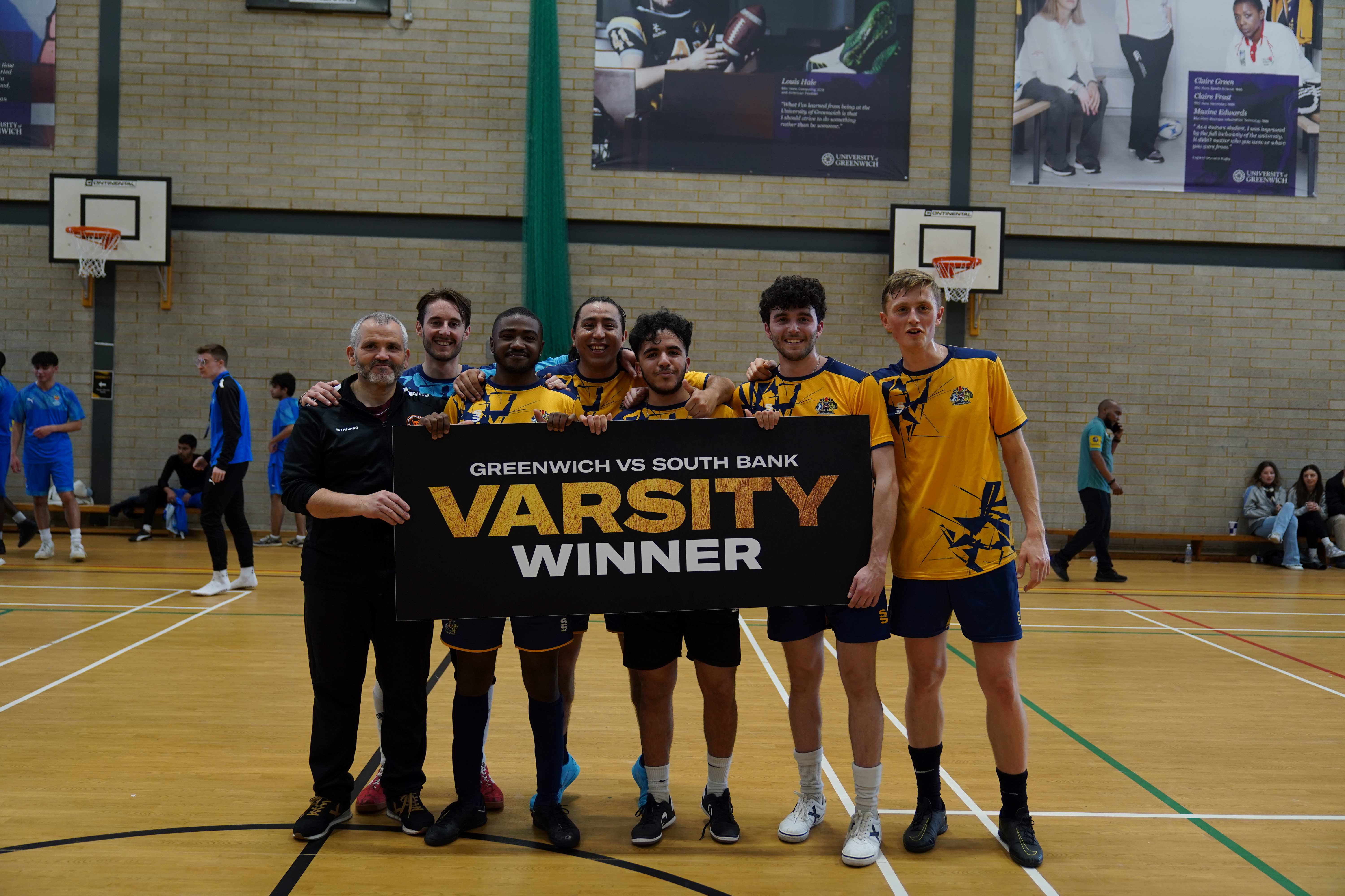 Photo of team of 7 men holding up 'varsity winner' sign