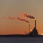 Emissions rising from industrial chimneys at sunset.