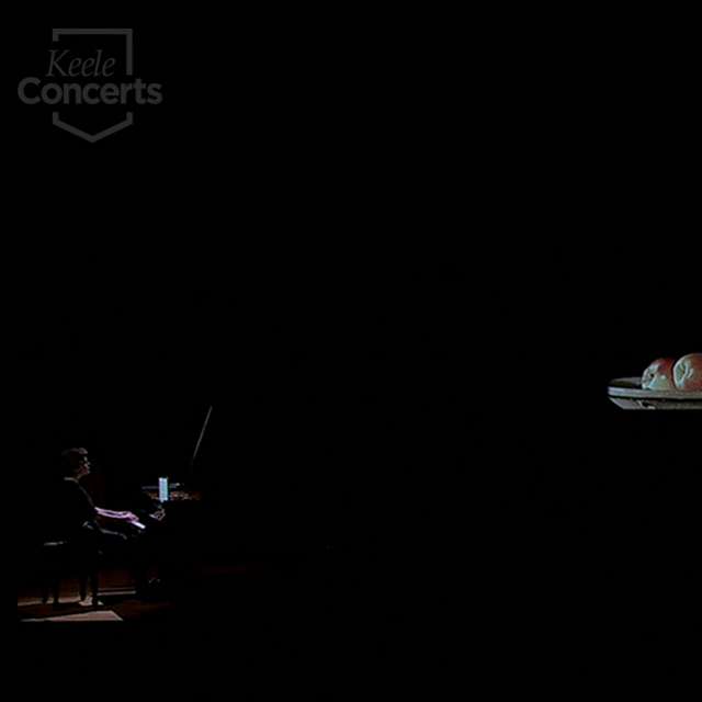 female at piano in darkened space with spotlight and projection of plate of apples