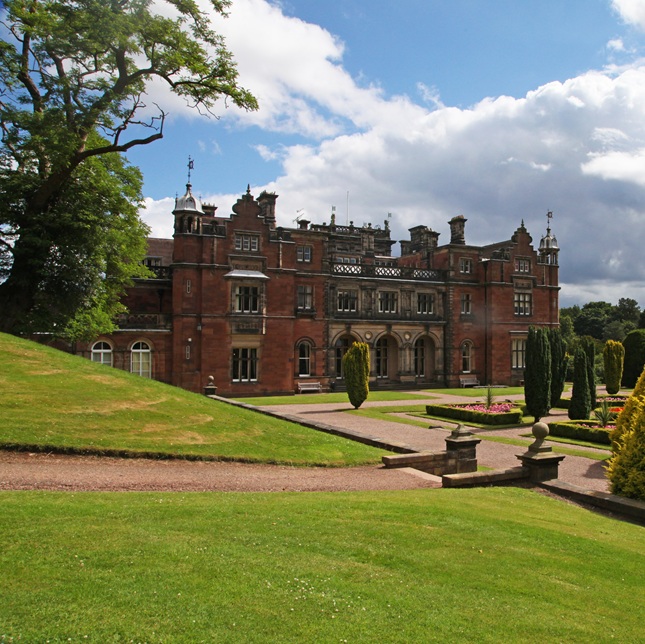 Stately building set in a green landscape with blue cloud filled skies