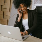 Happy person with phone at the right ear and left hand on laptop keyboard