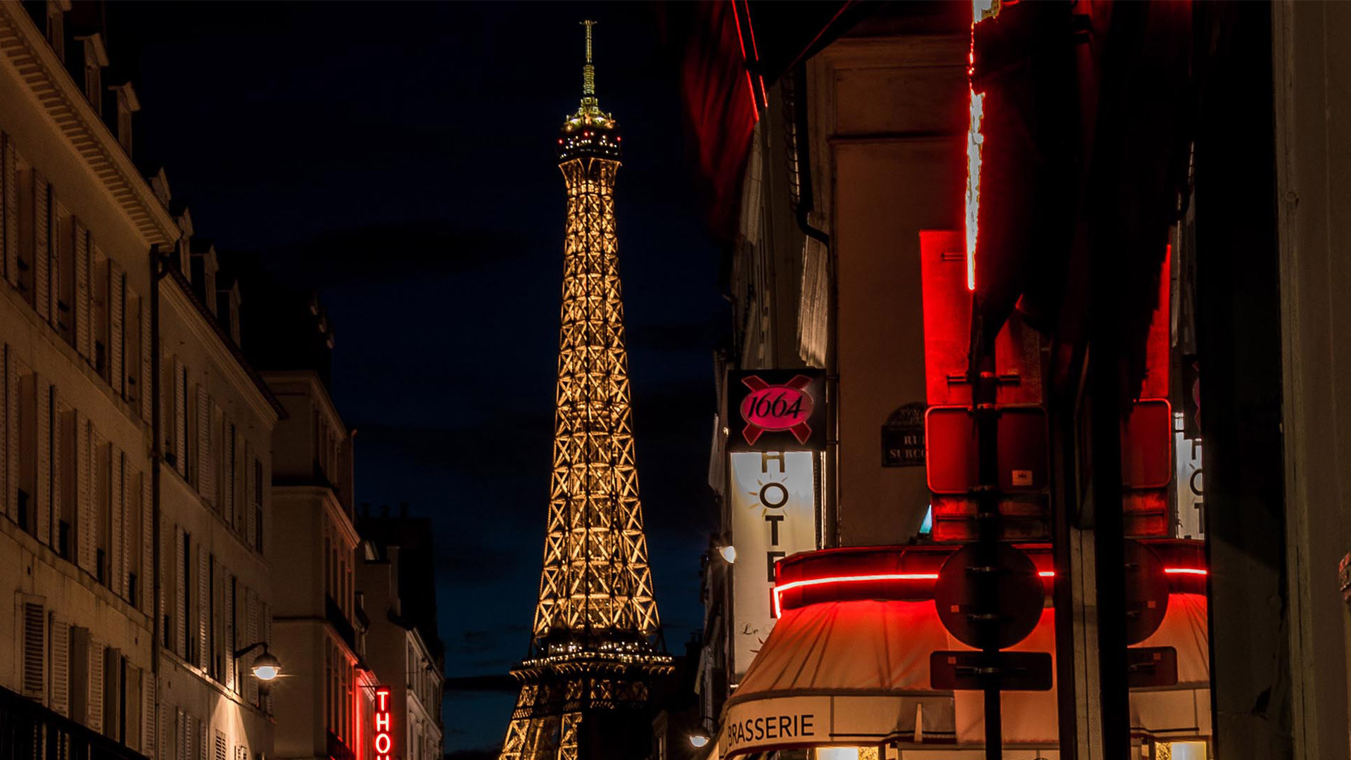 Image of a street in Paris, at nighttime with view of the Eiffel Tower.