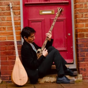 Shohret Nur with his instruments in front of a red door