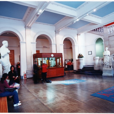 Image of a hall with students sat on a bench