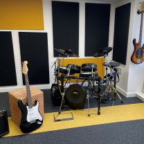Basement practice room with guitar, bass, electric drumkit and amps